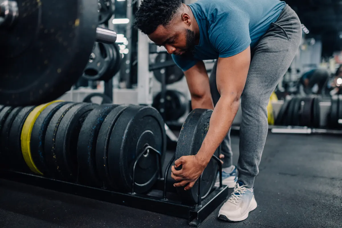 Home gym equipment marketing agency: young athlete preparing weights for his workout in the gym.