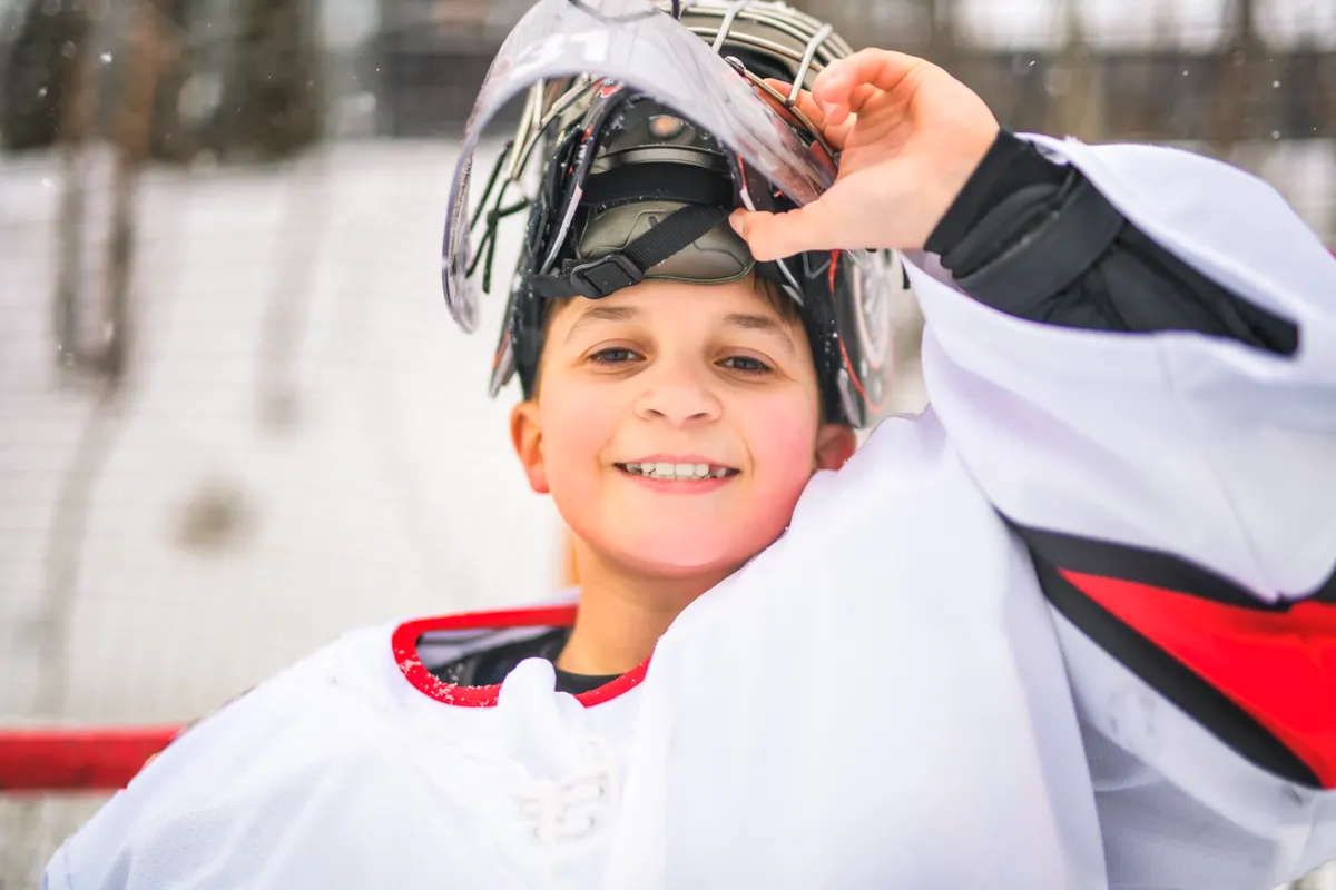 Team sports equipment marketing agency: ice hockey teen play hockey outside in uniform. Sports winter games outdoors in winter.