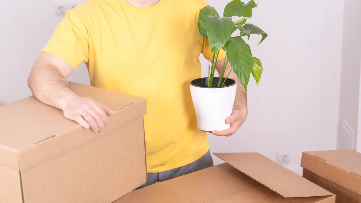 Plant subscription marketing agency: man in yellow shirt cradles a potted monstera.