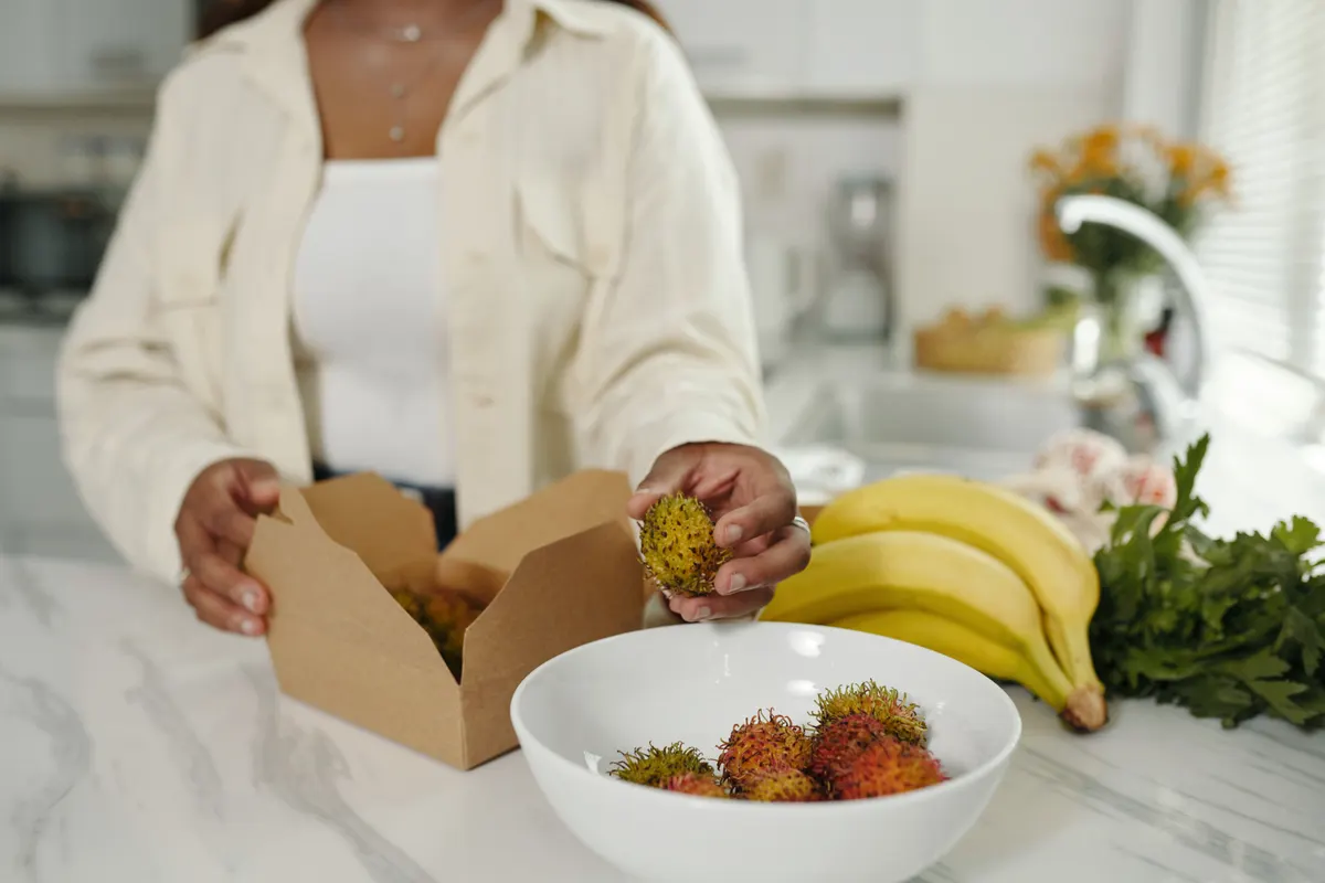 Snack subscription marketing agency: preparing Fresh Rambutan While Holding Open Box.