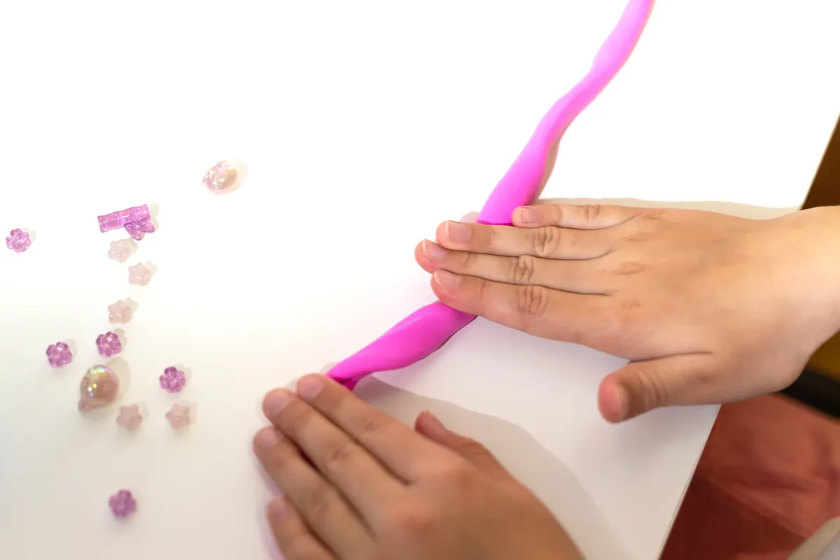 Sensory & slime marketing agency: child Stretching Pink Slime with Decorations.