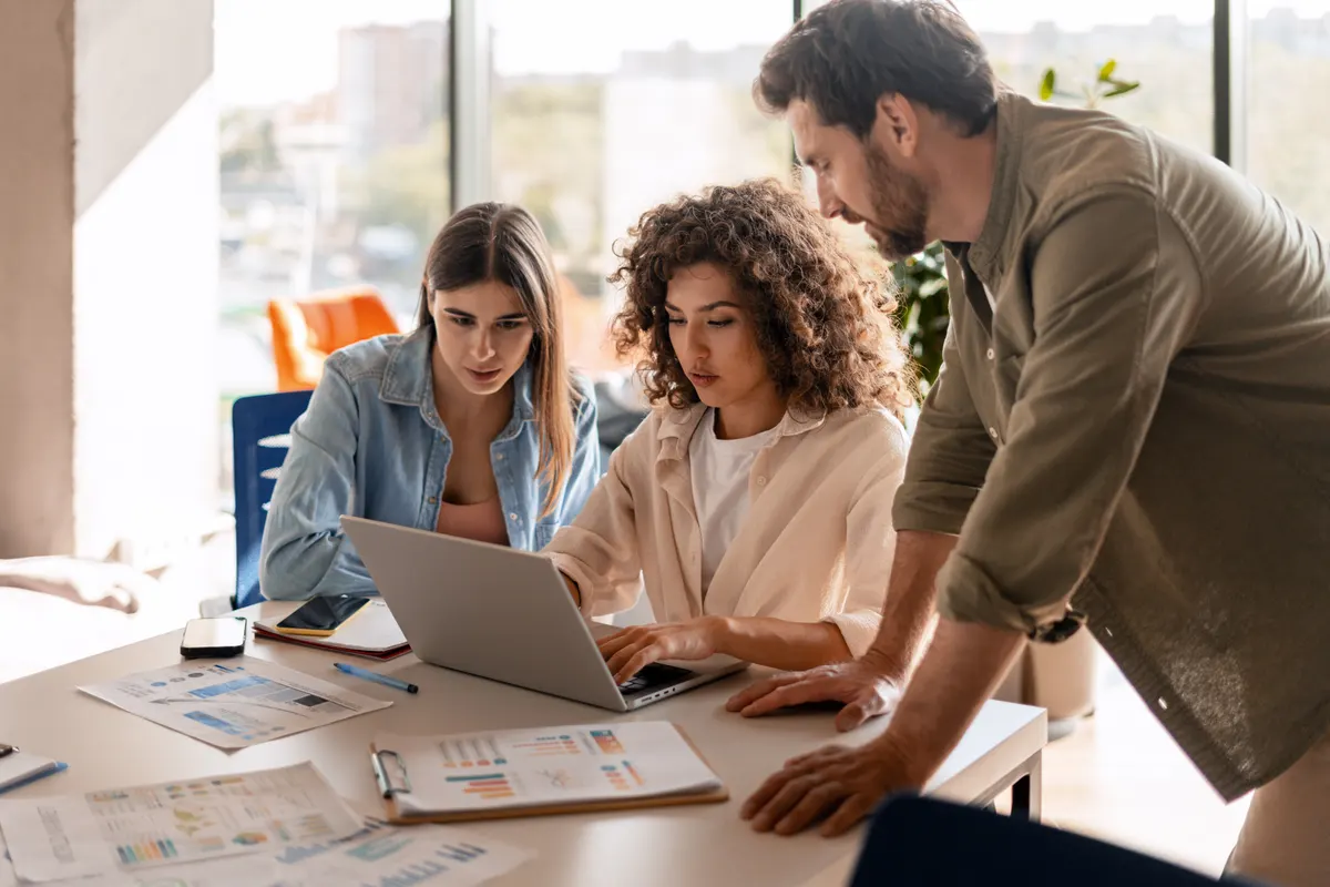Shopify SEO agency: focused colleagues working together on a laptop in modern office.