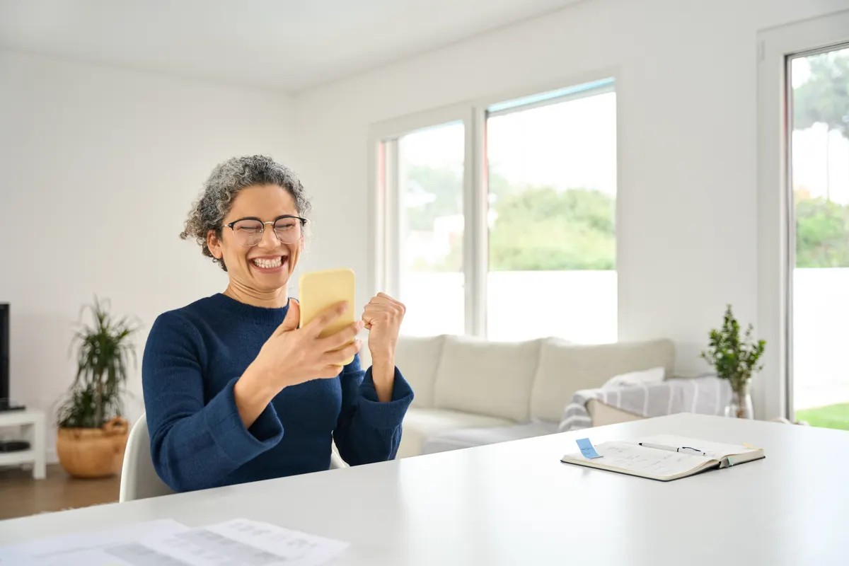 SMS marketing for ecommerce: happy mature woman customer celebrating win winning online on mobile phone.