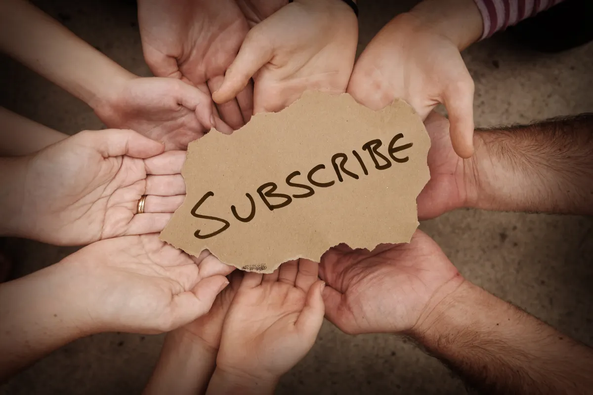 Subscription & retention marketing: subscribe Written on Cardboard Being Held by Group of People.